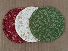 three circular coasters on a brown surface with red, white and green circles around them