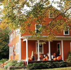 an orange house with pumpkins on the porch