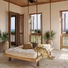 a bed sitting in the middle of a room next to two windows with shutters