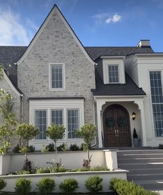 a large gray brick house with white trim on the front door and two story windows