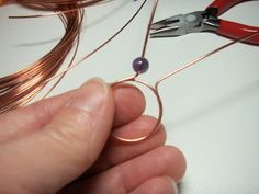 someone is cutting wire with scissors on a white counter top next to some copper wires