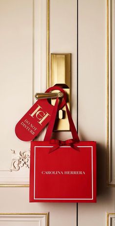 a red bag hanging from the side of a door with a name tag on it