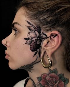 a woman with tattoos on her face and behind the ear is a grapes tattoo design