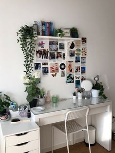 a white desk with some plants and pictures on the wall