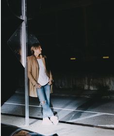 a woman standing next to a street sign at night