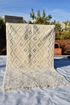 a white blanket sitting on top of a snow covered ground next to potted plants