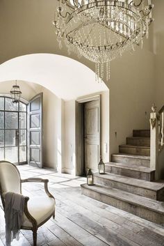 a chandelier hangs from the ceiling in front of a staircase leading up to an open door