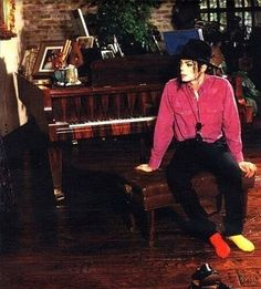 a man sitting on top of a piano in front of a brick wall and floor