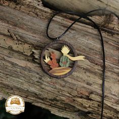 a wooden necklace with an acrylic painting of leaves and a bird on it