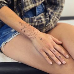 a woman's tattoo on her left arm is shown in the image, while sitting on a bed