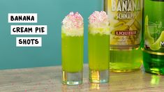 two glasses filled with green liquid and sprinkles on top of a table