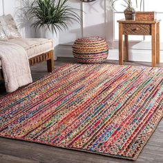 a multicolored rug in a living room next to a couch and table with potted plants