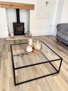 a glass table with candles on it in front of a wood burning stove and couch