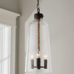 three candles are lit in a clear glass light fixture