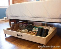 an open drawer underneath a bed filled with shoes