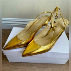 a pair of gold shoes sitting on top of a white box