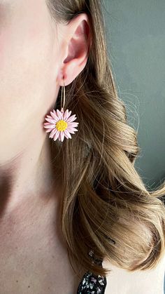 a close up of a person wearing earrings with a flower on the end of it