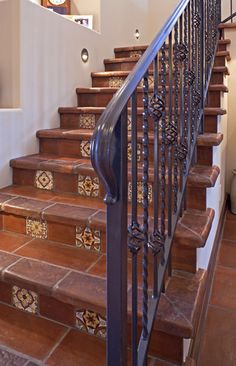 the stairs are made of wood and have decorative tiles on them, along with an iron handrail