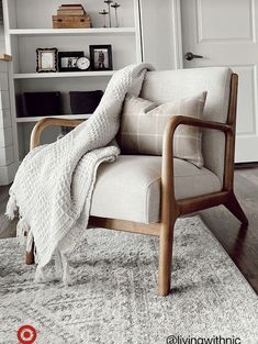 a chair with a blanket on it sitting in front of a book shelf filled with books