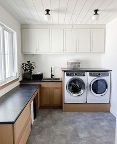 a washer and dryer sitting in a kitchen next to a counter with a potted plant on it