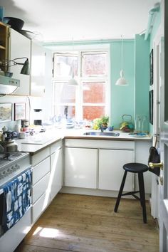 a kitchen with blue walls and white cabinets is seen in this image from the doorway