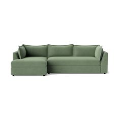 a green sectional couch with pillows on the top and bottom, in front of a white background