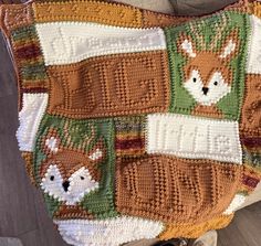 a crocheted blanket with animals on it sitting on top of a wooden floor