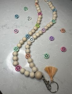 a wooden bead necklace with smiley faces on it and a tasseled keychain