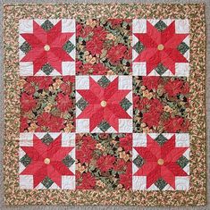 a red and white quilted wall hanging with poinsettia leaves on it