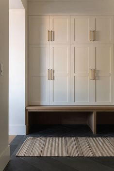 an empty room with white cabinets and striped rug