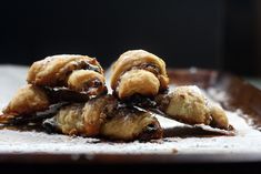 some food is sitting on top of a wooden tray with powdered sugar and chocolate