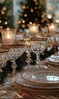 a table topped with lots of glass dishes and plates covered in christmas lights next to a tree