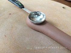 a spoon sitting on top of a piece of clay with a measuring spoon sticking out of it