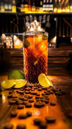 a tall glass filled with ice and lemons on top of a wooden table next to some cookies