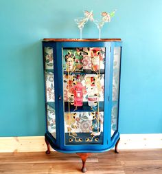 a blue cabinet with many items on it and two wine glasses in the top shelf