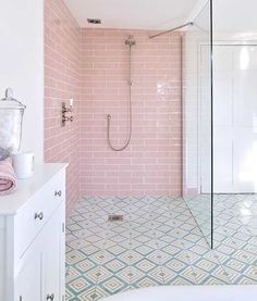 a bathroom with pink tiles on the walls and floor, along with a walk in shower