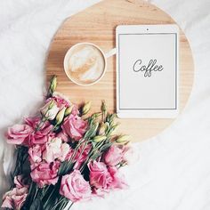 pink flowers and a tablet on a wooden tray with the word coffee next to it