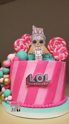 a pink and blue birthday cake with lol surprise on the top, surrounded by candy