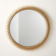 a mirror that has spikes on it and is hanging on the wall next to a white wall