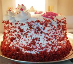 a large red velvet cake with white frosting and sprinkles on top