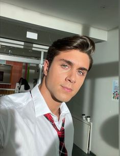 a man wearing a red tie and white shirt in an office setting with other people