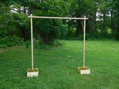 two planters sitting in the middle of a field near a wooden frame and some trees