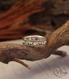 a silver and gold ring sitting on top of a tree branch