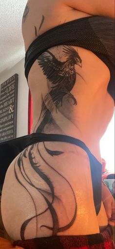 the back of a woman's stomach with a bird tattoo on her left side