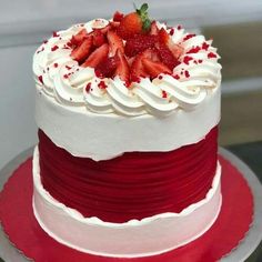 a red and white cake with strawberries on top is sitting on a platter