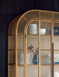 a wooden shelf with glass doors and vases