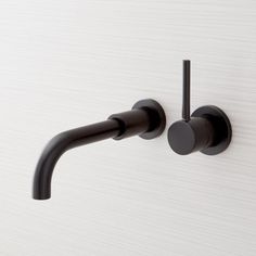 a black faucet mounted to the side of a white wall with two handles