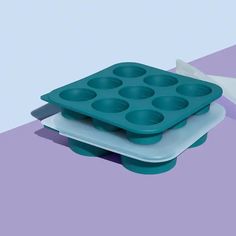 there are two trays with muffin pans on top of each other, one is blue and the other is white