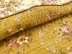 a yellow floral quilted bed spread with pink and white flowers on the bottom half