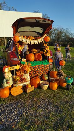 a car with pumpkins and other decorations on the hood is parked in a field